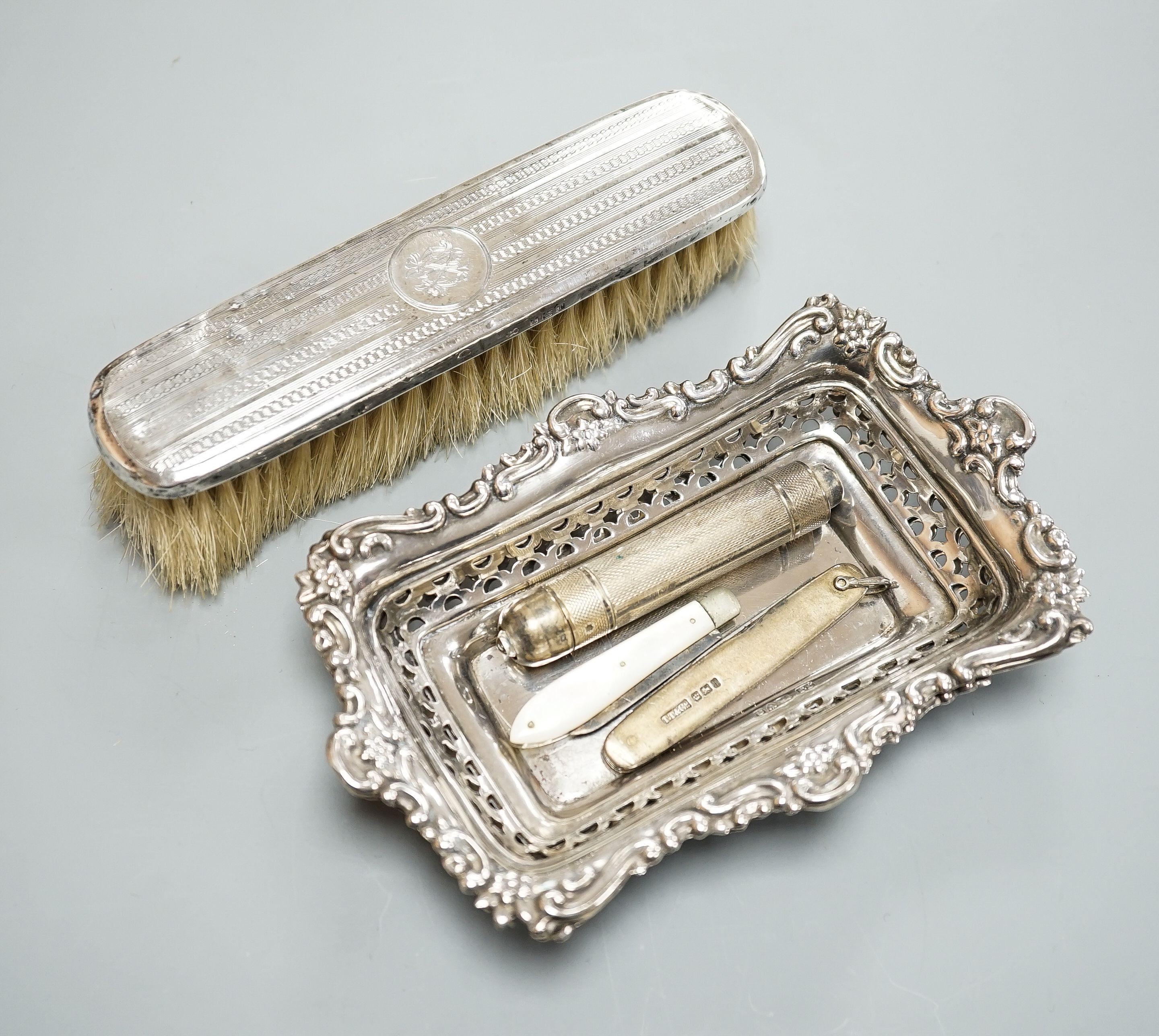 A pair of Edwardian pierced silver bonbon dishes, Chester, 1902, 16.1cm, 4.5oz, a silver and mother of pearl fruit knife, silver cased penknife and silver mounted clothes brush and a modern silver cased pocket torch.